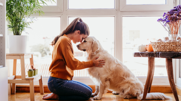 woman kneels with dog pressing her forehead into its. 